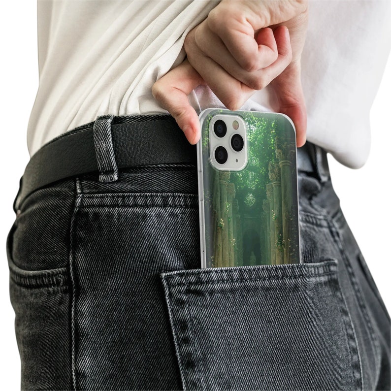 May include: A clear phone case with a green and white forest scene design. The case is in a back pocket of a pair of dark grey jeans.