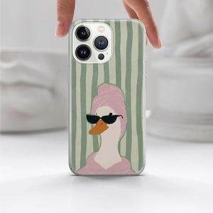 May include: A phone case featuring a cartoon duck wearing sunglasses and a pink towel, set against a background of vertical green stripes. The duck has an orange beak and is wearing black sunglasses.
