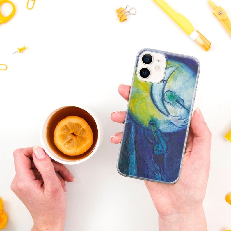 May include: A clear phone case with a colorful painting of a person playing a musical instrument in front of a crescent moon. The painting is in shades of blue, yellow, and green.