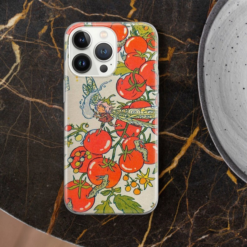 May include: A white iPhone case with a colorful illustration of tomatoes, a fairy, and insects. The case features a whimsical design with a red, green, and yellow color scheme.