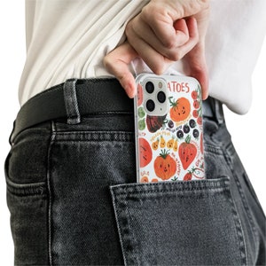 May include: A clear phone case with a colorful illustration of various fruits and vegetables. The case has the word "TOMATOES" printed on it.