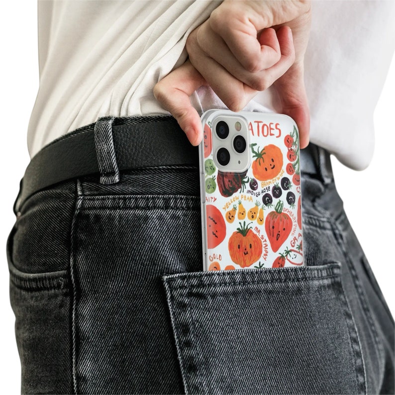 May include: A clear phone case with a colorful illustration of various fruits and vegetables. The case has the word "TOMATOES" printed on it.