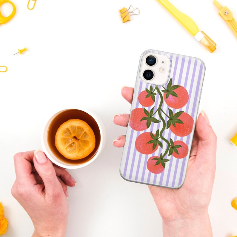 May include: A clear phone case with a purple and white striped background and a graphic of red tomatoes on a vine.