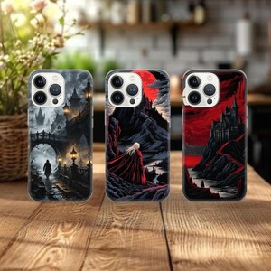 May include: Three phone cases with fantasy art. One case features a grayscale scene of a person walking on a bridge towards a castle. The second case shows a person in a red cloak with a castle and a red moon. The third case has a red and black castle scene.