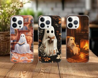 May include: Three phone cases with ghost illustrations. One case shows a ghost reading in a cozy room, another with a ghost reading a book, and the third with a ghost near a fireplace. The cases have a spooky, Halloween theme.