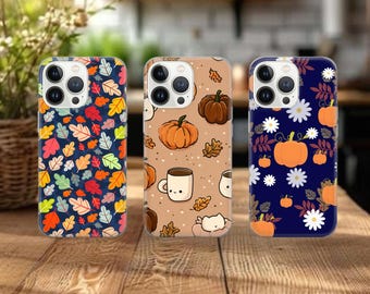 May include: Three phone cases with autumn-themed designs. One case features colorful leaves on a navy background. Another has pumpkins, coffee mugs, and leaves on a tan background. The third case displays pumpkins and white flowers on a navy background.