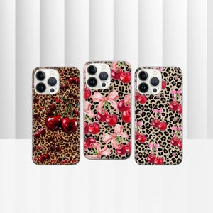 May include: Three iPhone cases featuring a leopard print background with red cherries and pink bows.