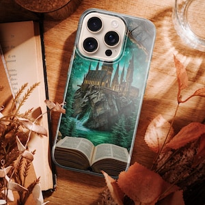 Fantasy-themed phone case featuring a majestic castle rising from an open book positioned on a rocky island. The scene is surrounded by glowing green and teal light, giving a magical and mysterious feeling. Tall castle towers reflect in the water below, while mist and light effects enhance the sense of fantasy and adventure. The illustration represents imagination, storytelling, and magical worlds coming to life from books.