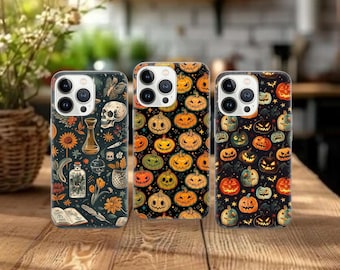 May include: Three phone cases with Halloween-themed designs. One case features a dark floral pattern with a skull and potion bottle. The other two cases have pumpkin patterns in orange, green, and yellow on a black background.