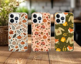 May include: Three phone cases with autumnal designs. One case features pumpkins and leaves, another has mushrooms and berries, and the third showcases foxes, mugs, and sweaters. The cases are on a wooden surface.