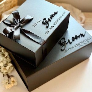 May include: Two black gift boxes, one on top of the other, tied with a satin ribbon and bow. The top box has the words "TO MY Groom ON OUR WEDDING DAY" in black script. The bottom box has the word "Groom" and the date "06.20.26".