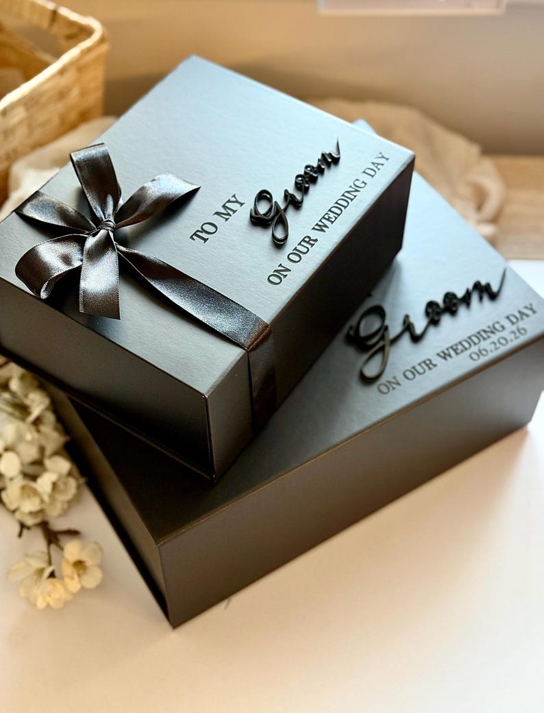 May include: Two black gift boxes, one on top of the other, tied with a satin ribbon and bow. The top box has the words "TO MY Groom ON OUR WEDDING DAY" in black script. The bottom box has the word "Groom" and the date "06.20.26".