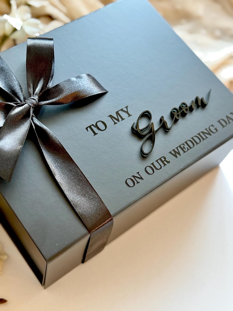 May include: A grey gift box tied with a dark grey satin ribbon and bow. The box is inscribed with the words "TO MY Groom ON OUR WEDDING DAY" in dark grey.