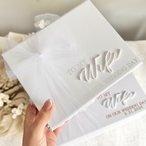 May include: White wedding keepsake box with the text "TO MY Wife ON OUR WEDDING DAY" in elegant script. The box is adorned with a delicate white tulle bow. A second box is visible with the date 5.21.2026.