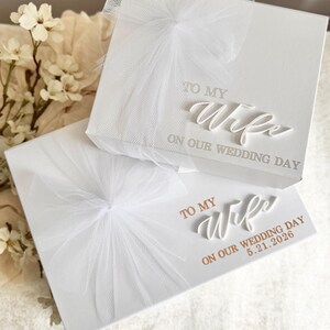 May include: Two white gift boxes with tulle bows. The top box reads "TO MY Wife ON OUR WEDDING DAY" in elegant script. The bottom box has the same text, with the addition of "5.21.2026".