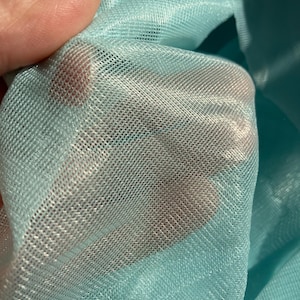 May include: A close-up of a light blue sheer fabric with a fine mesh texture. The fabric is soft and delicate, with a subtle shimmer.