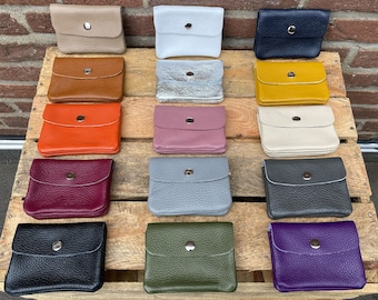 May include: Assortment of 15 small leather wallets in various colors, including black, white, gray, brown, orange, purple, green, and pink. Each wallet has a single snap closure.