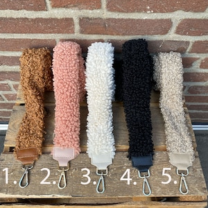 May include: Five different coloured fuzzy fabric straps with metal clasps. The straps are numbered 1 through 5.