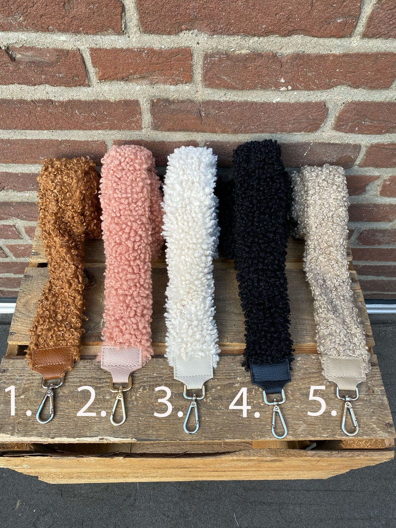 May include: Five different coloured fuzzy fabric straps with metal clasps. The straps are numbered 1 through 5.