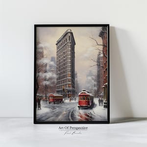 Puede incluir: Una pintura del Flatiron Building en la ciudad de Nueva York, cubierto de nieve. Dos tranvías rojos están en primer plano, con gente caminando por la calle nevada. La pintura se titula "Art Of Perspective" de Paul Brandt.