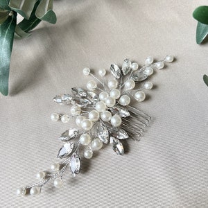 Wunderschöner Brauthaarkamm in Silber, verziert mit weißen Perlen und Strasssteinen für eine elegante Note. Ca. 15 cm lang und 7 cm breit. Die funkelnden Strasssteine werten jede Frisur auf. Perfekt für Braut, Trauzeuginnen und Brautjungfern