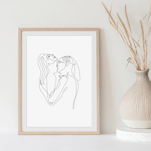 Può includere: Una stampa artistica da parete incorniciata con un disegno a linee nere su sfondo bianco. L'opera raffigura due figure in un abbraccio intimo, con una figura che tiene la testa dell'altra. La cornice è in legno chiaro dal profilo semplice.