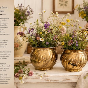 May include: Two antique brass planters with a swirling pattern, overflowing with vibrant wildflowers. The planters have a rich patina and are displayed on a white surface. The image also shows text that reads "Vintage Brass Planters".