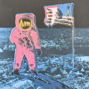 Puede incluir: Impresi&oacute;n de arte pop de un astronauta con un traje espacial rosa de pie sobre una superficie lunar azul y gris junto a una bandera estadounidense. El casco del astronauta refleja una imagen amarilla y negra. La bandera es roja, blanca y azul.