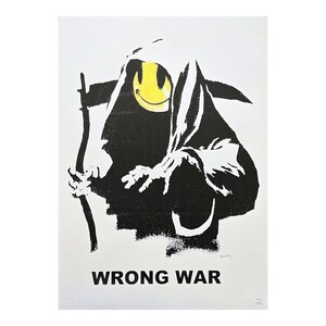 Puede incluir: Impresión de arte en stencil en blanco y negro de la Muerte con una cara sonriente amarilla. La Muerte sostiene una guadaña y el texto "WRONG WAR" está impreso debajo de la imagen.