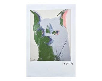 May include: A close-up of a colorful print of a dog's face. The dog's fur is white with green and blue accents. The dog's ears are pink and the background is white. The print is signed "Warhol" in the bottom right corner.
