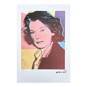 May include: Pop art print featuring a portrait of a woman with dark hair, rendered in vibrant colors. The artwork has a signature in the lower right corner and is set against a backdrop of pink, yellow, purple, and blue hues. The print is on white paper.