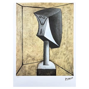 Puede incluir: Una escultura abstracta de una cabeza en blanco y negro en una habitación con fondo dorado. La escultura está sobre un pedestal. La firma del artista "Picasso" está en la esquina inferior derecha.