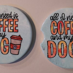 May include: Two blue and white ceramic coasters with a coffee cup and the text "all I need is coffee and my dog" in orange and yellow lettering.