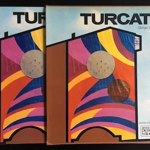 May include: Two book covers with a colorful abstract design featuring a yellow, orange, red, pink, blue, and purple color scheme. The title "TURCATO" is printed in black on the cover. The text "Giorgio de Marchis" is printed in black below the title. The text "GRANDE OPERE MONOGRAFICHE" is printed in black at the bottom of the cover. The text "stampato presso editore" is printed in black in a box at the bottom of the cover.
