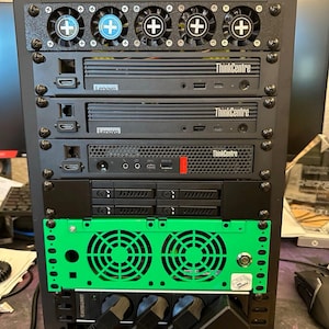 Könnte beinhalten: Ein schwarzes Server-Rack mit mehreren Komponenten, darunter Lenovo ThinkCentre-Computer und grüne Lüfter. Das Rack hat mehrere Lüfter mit Plus-Symbolen und verschiedene Anschlüsse.