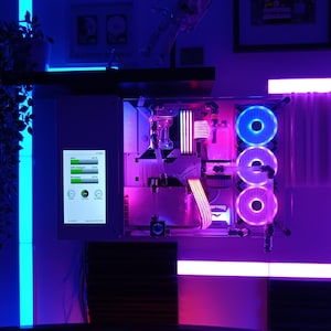 Può includere: Un case per computer bianco con pannelli laterali trasparenti, che mostra un PC personalizzato con illuminazione RGB. Il case ha tre ventole con luci LED blu e rosa. Il computer è montato su una scrivania con luci LED blu e rosa attorno ai bordi.