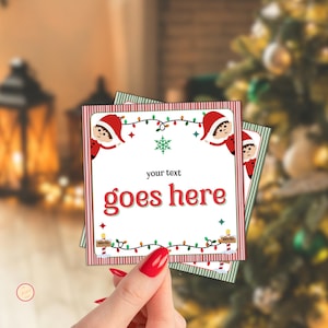 Könnte beinhalten: Quadratische Weihnachtskarten mit rot-weiß gestreiftem Rand. Die Karten zeigen ein festliches Design mit einem Elf, Lichterketten und dem Text "your text goes here". Die Karten werden in der Hand einer Person gehalten.