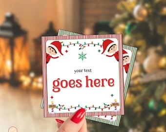 Puede incluir: Tarjetas de Navidad cuadradas con borde a rayas rojas y blancas. Las tarjetas presentan un diseño festivo con un elfo, luces de cadena y el texto "your text goes here". Las tarjetas están en la mano de una persona.