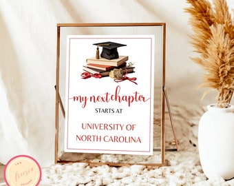 May include: A framed graduation sign with the text "my next chapter starts at UNIVERSITY OF NORTH CAROLINA" in red script. The sign features a stack of books, a graduation cap, and a rolled diploma. The frame is gold-colored.