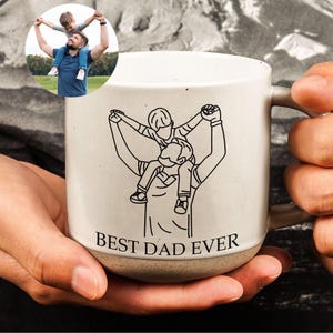 May include: White ceramic mug with a black line drawing of a father carrying a child on his shoulders. The mug has the text "Best Dad Ever" printed on the bottom.