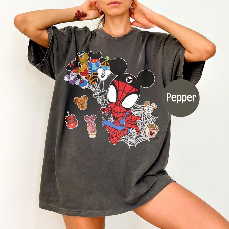 Puede incluir: Camiseta gris oscuro con un personaje de dibujos animados de Spider-Man con orejas de Mickey Mouse, sosteniendo globos con Mickey Mouse y otros dise&ntilde;os de personajes. La camiseta tiene un dise&ntilde;o de telara&ntilde;a y la palabra "Pepper".