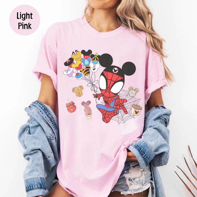 Puede incluir: Camiseta rosa claro con un personaje de dibujos animados de Spider-Man con orejas de Mickey Mouse, sosteniendo globos con cabezas de Mickey Mouse. La camiseta tambi&eacute;n tiene varios gr&aacute;ficos de comida con tem&aacute;tica de Disney. Las palabras "Light Pink" est&aacute;n en un c&iacute;rculo rosa claro en la esquina superior izquierda.