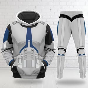 May include: A two-piece outfit featuring a white, gray, and blue design reminiscent of a stormtrooper uniform. The hooded sweatshirt has a front pocket and the pants have a matching design. The outfit is displayed against a white brick wall.