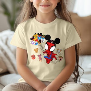Puede incluir: Camiseta beige claro con una ilustraci&oacute;n de dibujos animados de Spider-Man con orejas de Mickey Mouse sosteniendo globos. Los globos est&aacute;n dise&ntilde;ados como varios personajes de Disney. Tambi&eacute;n se incluyen golosinas tem&aacute;ticas de Disney y una telara&ntilde;a.