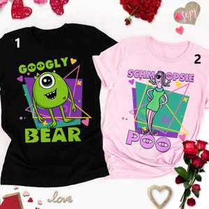 May include: Two black and pink t-shirts with a graphic print of cartoon characters. The black shirt has a green monster with one eye and the text "Googly Bear". The pink shirt has a purple creature with the text "Schmoopsie Poo".