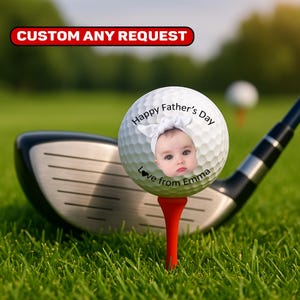 May include: A golf ball on a red tee with a baby's face and the text "Happy Father's Day, Love from Emma." A golf club is in the background, with the text "CUSTOM ANY REQUEST" at the top.