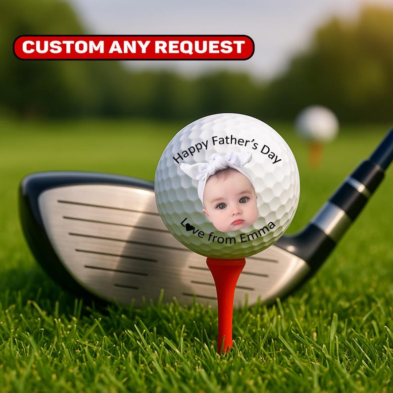 May include: A golf ball on a red tee with a baby's face and the text "Happy Father's Day, Love from Emma." A golf club is in the background, with the text "CUSTOM ANY REQUEST" at the top.