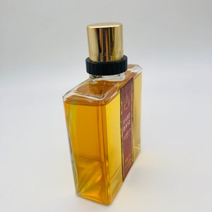 May include: A clear glass bottle of Guerlain Habit Rouge perfume with a gold cap and a red label. The label reads "Habit Rouge Guerlain Eau de Cologne".