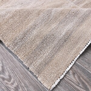 Pu&ograve; includere: Primo piano di un tappeto beige con un bordo di frangia bianca. Il tappeto &egrave; realizzato in un materiale morbido e tessuto e ha una texture sottile.