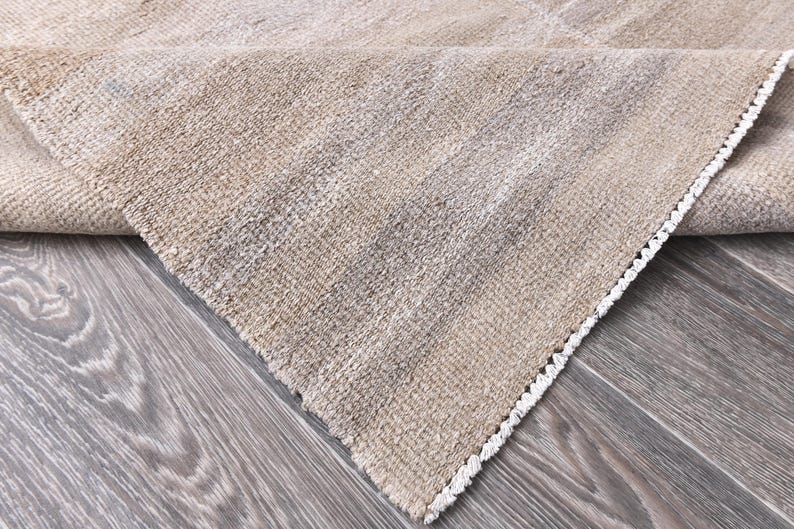 Pu&ograve; includere: Primo piano di un tappeto beige con un bordo di frangia bianca. Il tappeto &egrave; realizzato in un materiale morbido e tessuto e ha una texture sottile.